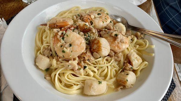 Seafood over linguine in a buttery broth full of fresh clams