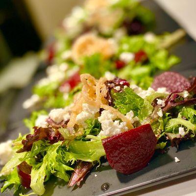 Poached beet salad with red wine beets, mixed greens, goat feta, crispy shallots, and grated walnuts