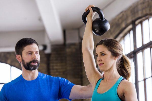 Trainer Matt Semrick working with a client on an overhead press.