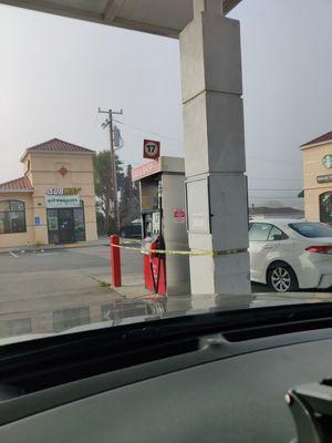 Gas station dispenser with yellow tape.