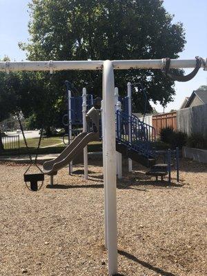 Swing in front, play area behind, benches, grass area behind that. Sun overhead made pics iffy