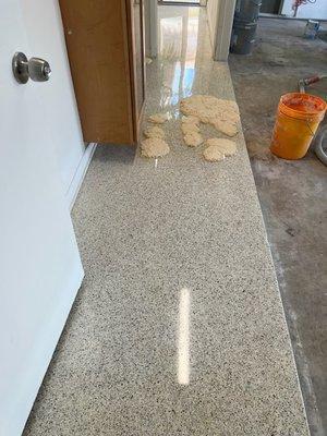 This refinish Terrazzo Floor had some stains on. It was right next to the garage, application of stain remover from the orange bucket