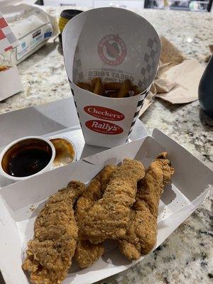 Seasoned chicken tender with large fries.