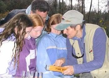 Volunteer naturalist shows a group of children the different life stages of salmon.