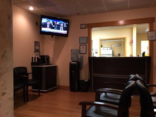 The waiting room with water, coffee, and a TV