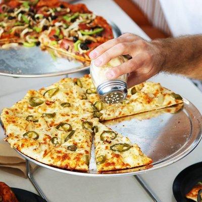 Cheesy jalapeño pizza topped with finely grated parmesan cheese.