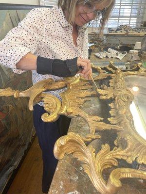 Repairing broken cartouche on an ornate gilded frame.