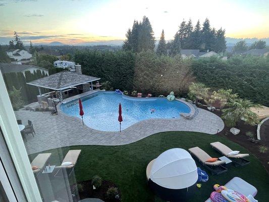 Custom infinity edge pool with swim up bar, outdoor kitchen, and diving boulder.