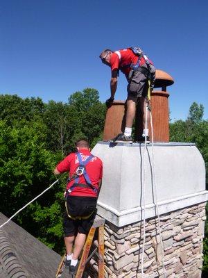 Working on a leaking chimney way up high, wearing our safety harnesses.