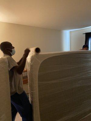 Applying shrink wrap to a mattress.