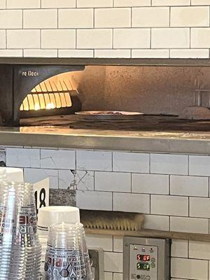 Gluten free pizza in the pan in the oven separated from the items with gluten.