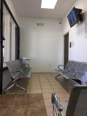 small waiting room with strong metal benches approx 13 seats total