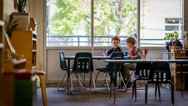 Two students work together in a natural light-filled room.