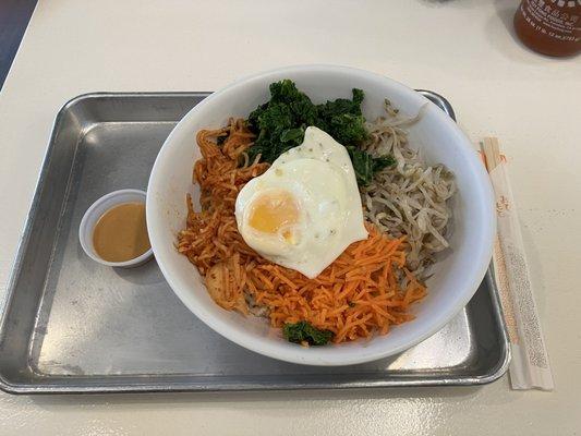 Gluten-free rice bowl w/ carrot, bean sprouts, kale, radish salad and an egg, peanut sauce in the side.