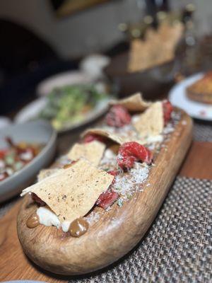 Black pepper charred filet mignon carpaccio with horseradish, shaved parmesan, black garlic aioli, and a house made herbed lavash.