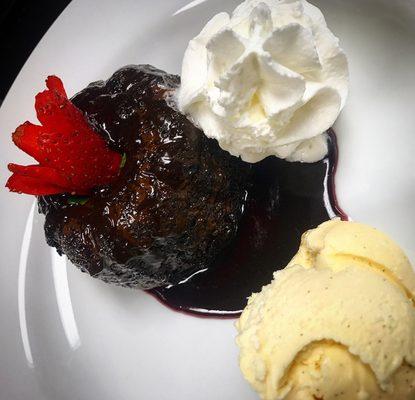 Molten Chocolate Lava Cake with vanilla ice-cream and whipped cream on top of raspberry puree