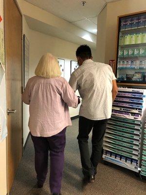 their summer intern, Thai (sp?), carefully escorting my 94 yr old mother to the exam room (she needs help walking).