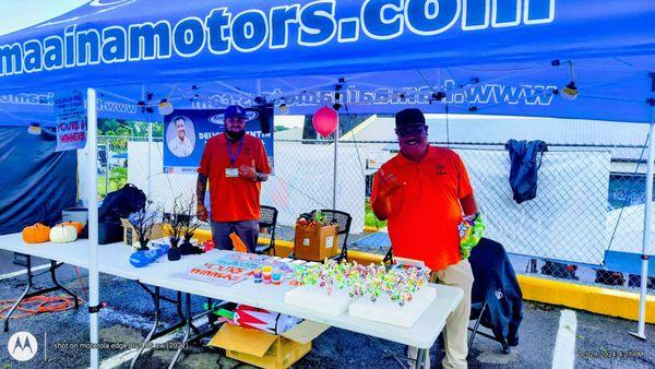 YMCA Hilo 2024 Halloween Carnival, 10/29. "Lollipop Pull" game, Jon & Delvin @ the Kamaaina Motors tent. Impressive interaction + smiles!