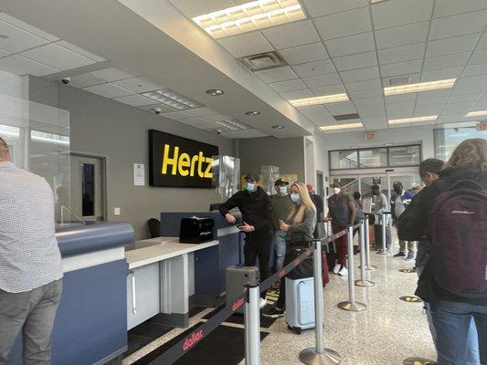 13 people wait for help by 1 counter person for 2 rental companies.