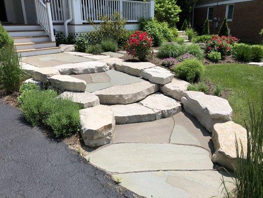 A custom stone entryway with colorful shrubs, grasses, and perennials...