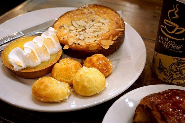 Chouquettes ($0.45 each) in front. Tarte au Citron ($3.75) in back left. Brioche Bostock ($3.80) in back right. Latte ($4.40 for 16oz).