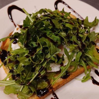 Avocado toast with arugula, fresh tomato, an egg, and balsamic drizzle.