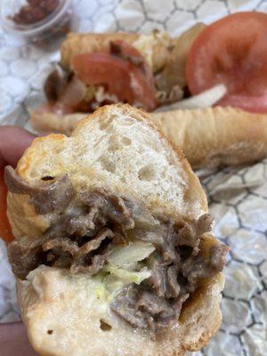 Philly cheesesteak with tomato, lettuce, and grilled onions