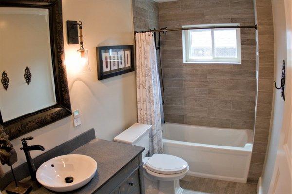 Wood tile plank flooring and distressed vanity offer a rustic feel that was perfect for the home owner.