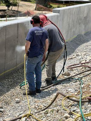 Blasting concrete to expose the stone underneath.