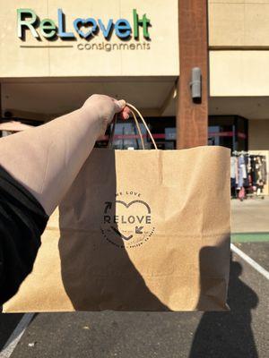 Holding up a cutely branded paper bag from Relove.