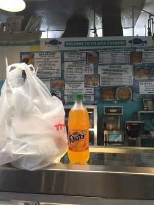 Bag of food and mango Fanta with the menu in the background