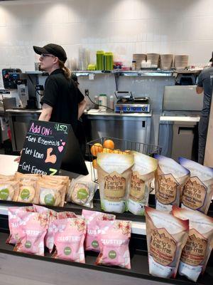 A view while standing by the cashier of the food prep area and snacks near the register.