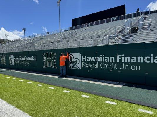 Banners installed at University of HI football stadium for sponsor advertising.