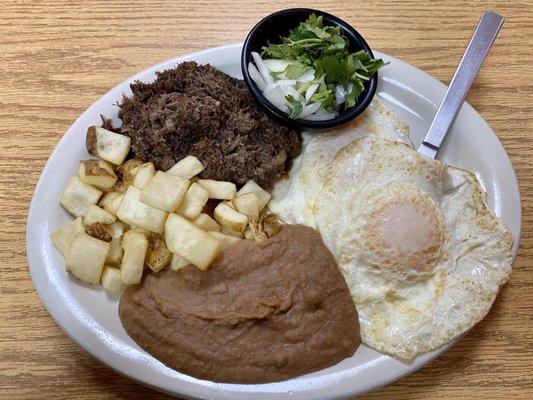 Barbacoa plate with sunny side up eggs, fried potatoes and refried beans