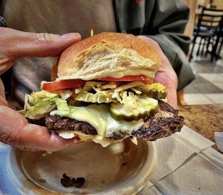 My husband about to bite into a - worlds greatest cheeseburger deluxe( which means with lettuce, tomato mayo, and he added pickles!