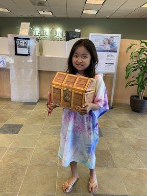 My daughter ready to deposit the money in her treasure chest~