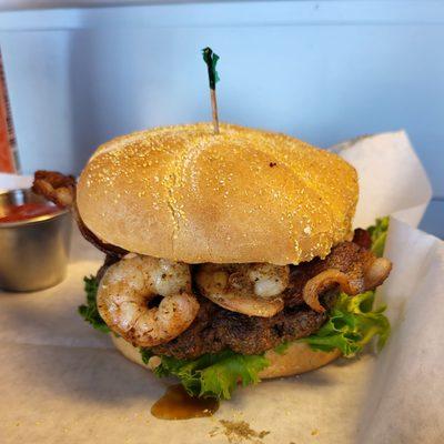 Surf 'N Turf: 1/3lb beef patty, topped w/Old Bay fried shrimp, thick cut hickory bacon, lettuce and a house-made Sriracha Aioli.