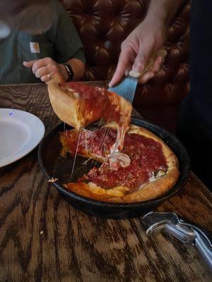 Serving the pie, there's so much cheese it almost got away!