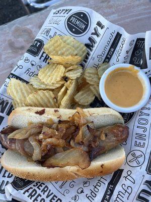 Beer braised brat with grilled onions, beer cheese on the side and kettle chips