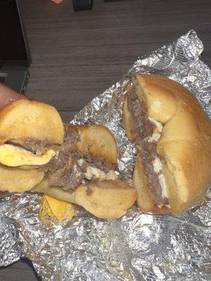 steak, egg, cheddar cheese with fried onions on an egg bagel