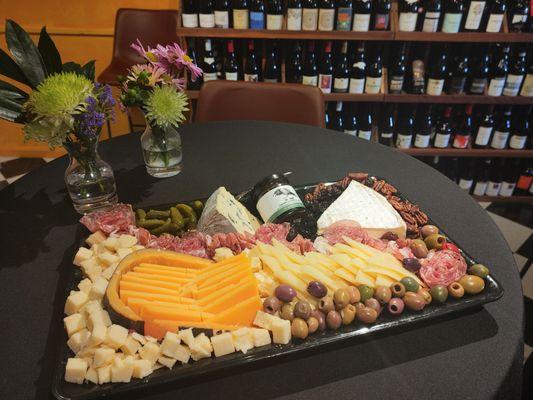 A large custom charcuterie board with a selection of cheeses, meats, jams, fruit, nuts, and pickled items.