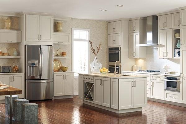 Kemper cabinetry in cream color with large island featuring stainless steel appliances and tile backsplash.