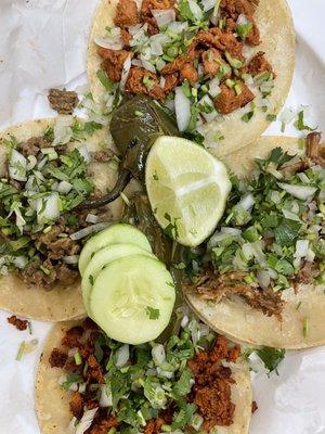 Various Tacos with slices cucumbers, lime and grilled jalapeños.