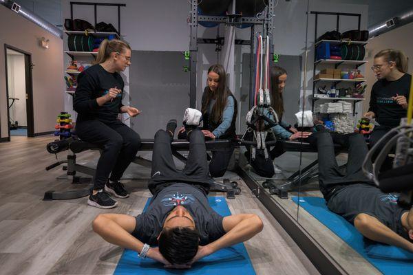 Nurse and therapist guiding client through rehab exercises