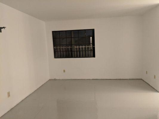 Finished room with fresh white sealant on walls, newly painted ceiling, and a double-coat of sealant on the floor for added protection.