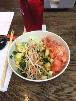 Salmon Poke Bowl: daikon shoots,green onions, cucumbers and avocado. Hard white rice on bottom. Sriracha soy sauce on top