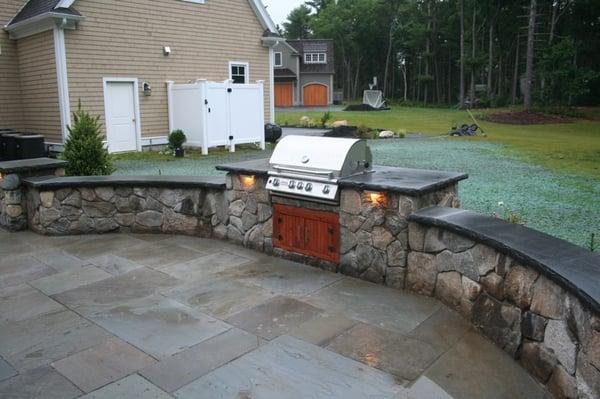 An outdoor cooking area with Fieldstone veneer and Bluestone caps with a rockfaced edge.