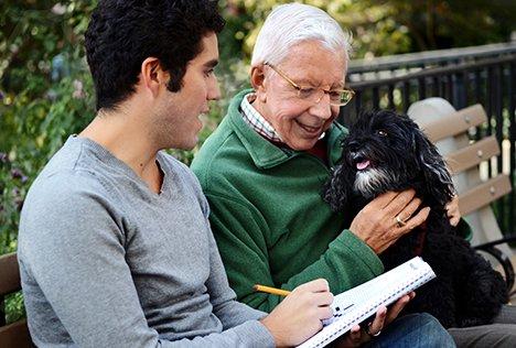 Gilbert, a Broadway producer, enjoys exploring city parks with his service dog and Care Partner Mario, an actor.