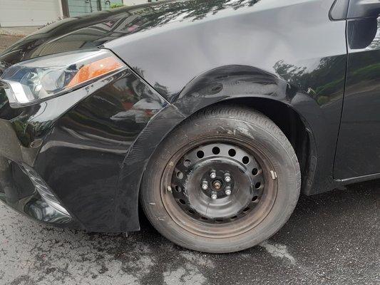 Panel above driver's side wheel dented and front bumper scratched.