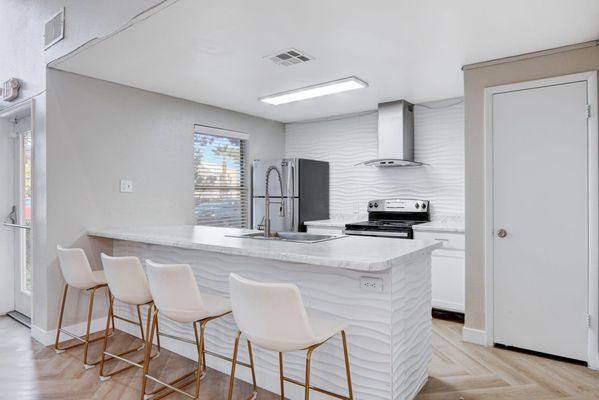 Clubroom kitchen with barstool seating and white countertops